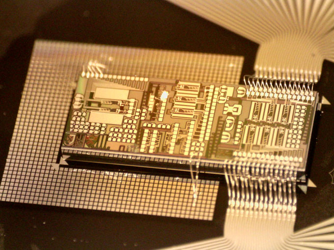 A close-up of a chip that Bhavin Shastri's team developed. The color of the chip is gold.